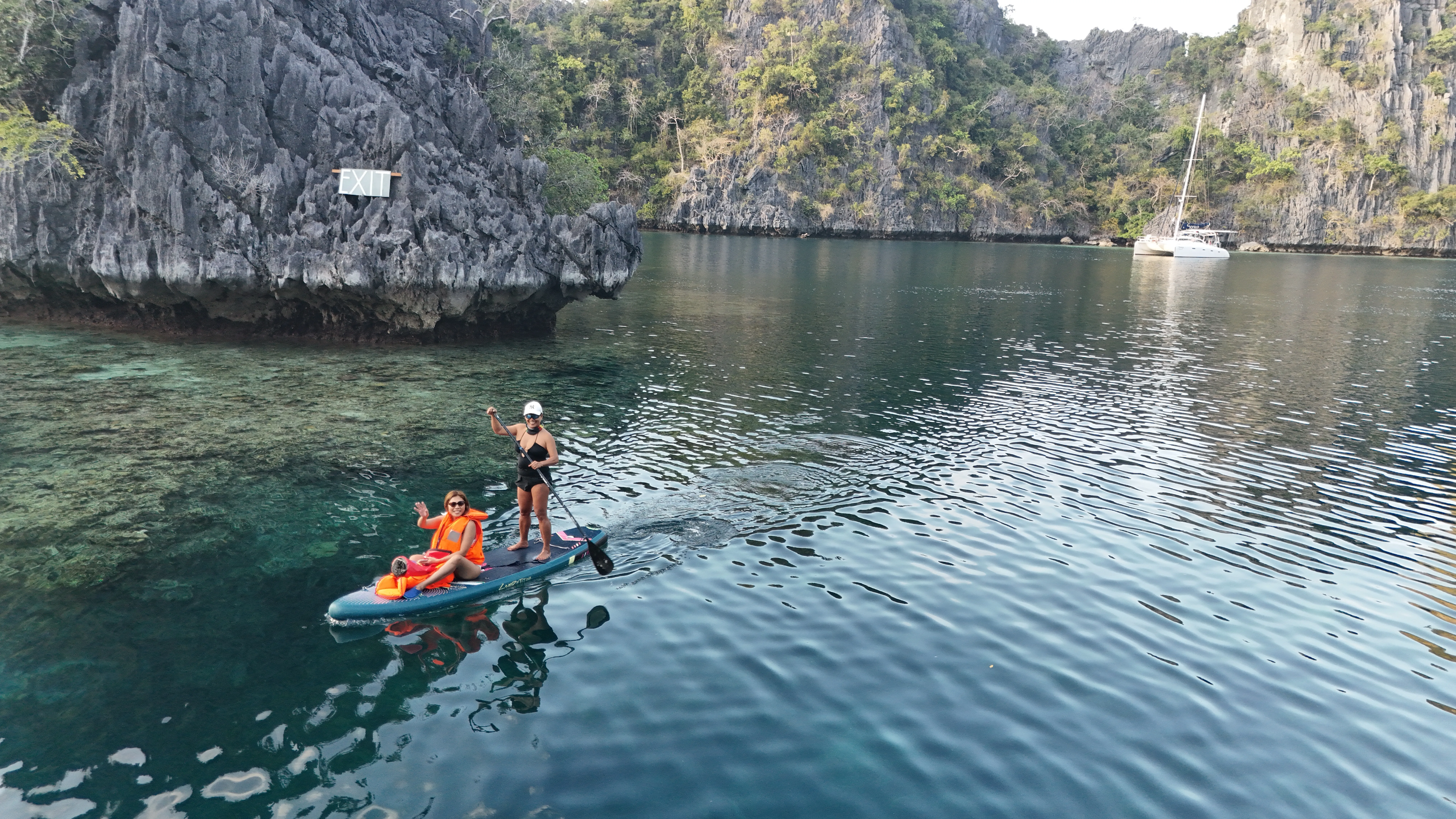 Guests paddleboarding past limestone cliffs